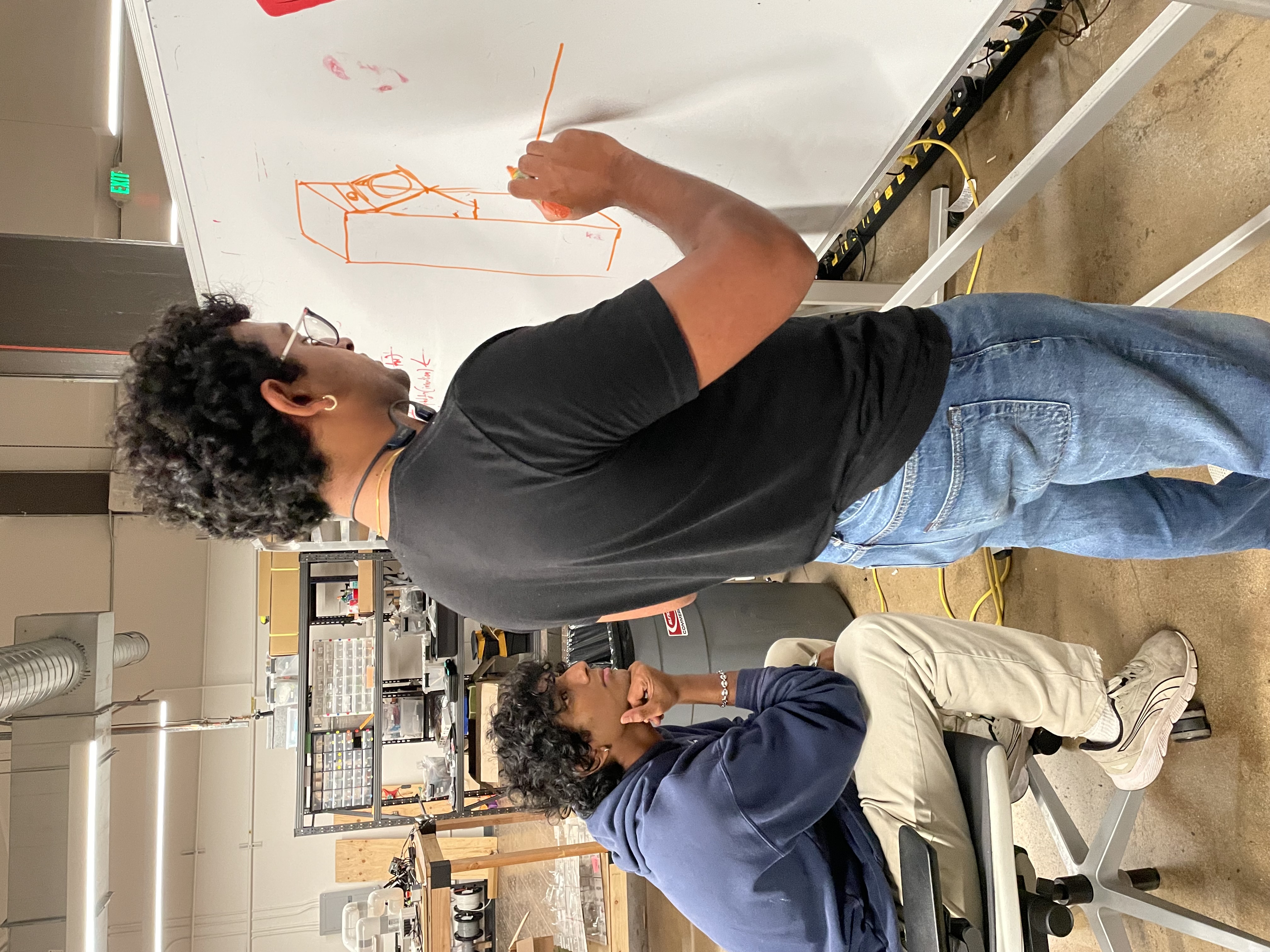 Team designing robot arm on whiteboard